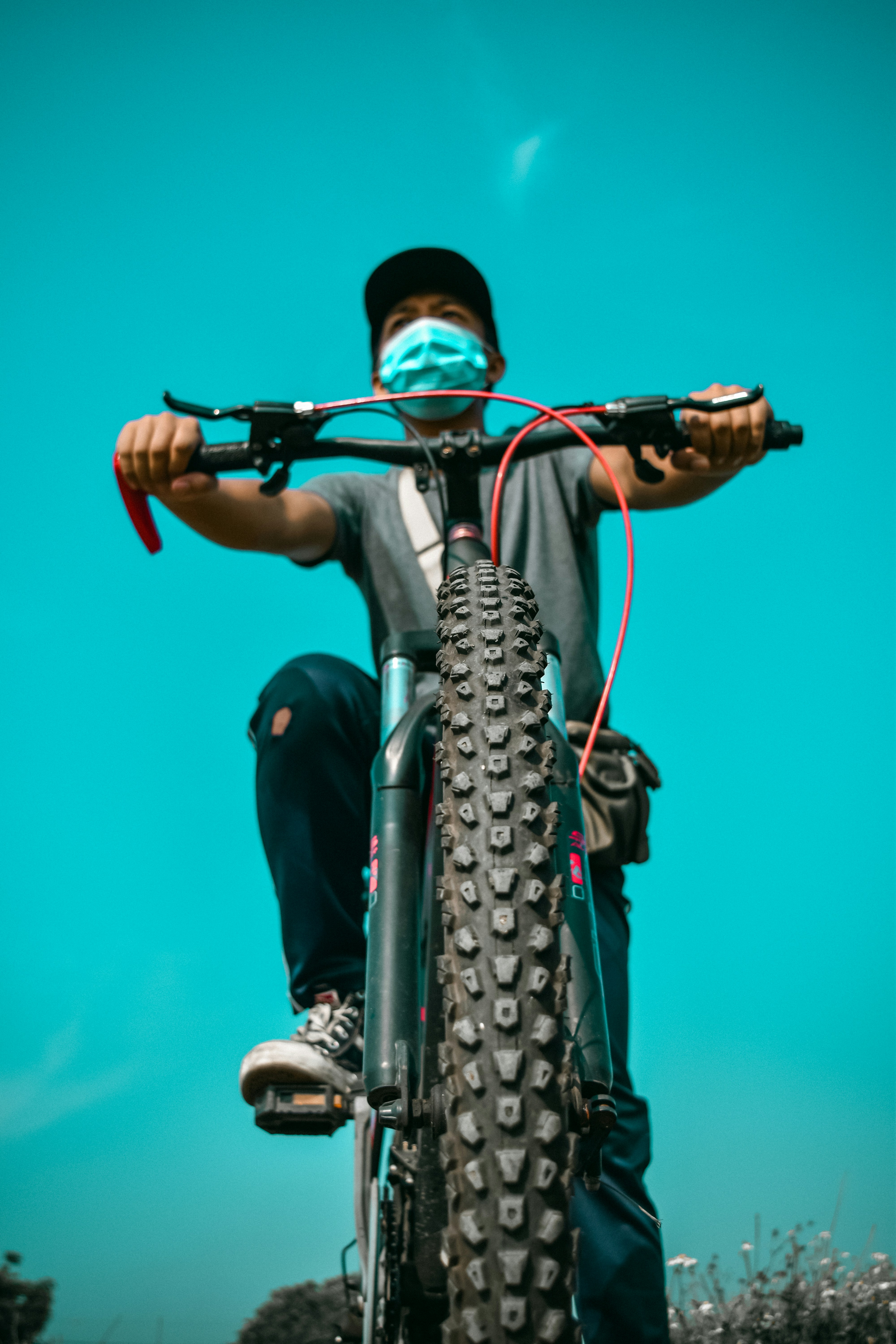man in black t-shirt and blue denim jeans riding bicycle