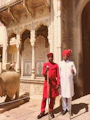 man in red robe standing near white concrete building during daytime