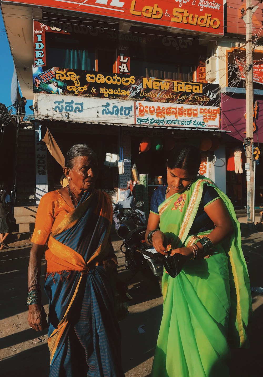 Femme en sari jaune et bleu debout sur le trottoir pendant la journée