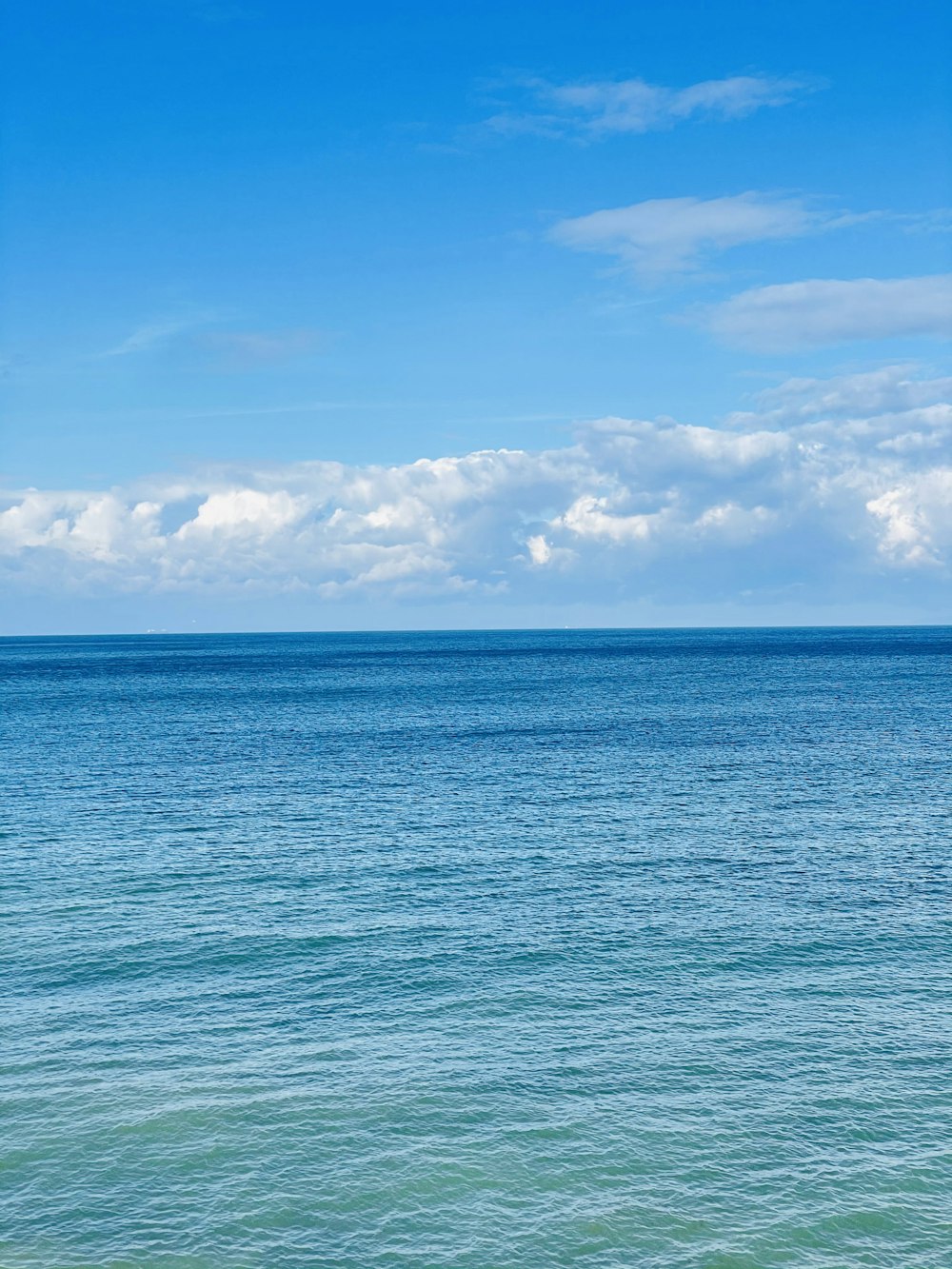 blue sea under blue sky and white clouds during daytime