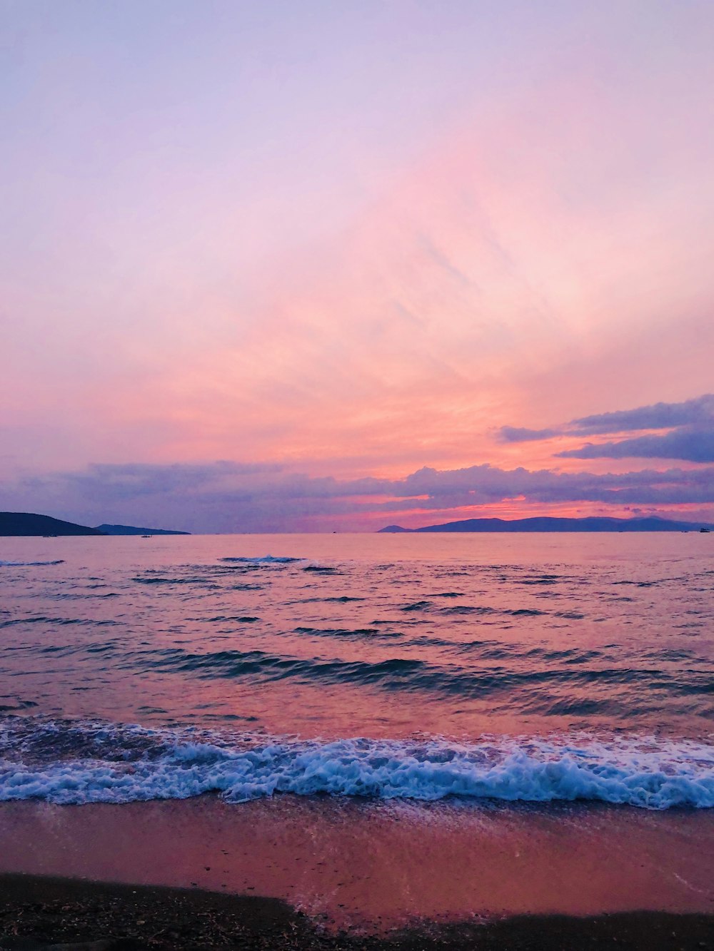 ocean waves crashing on shore during sunset