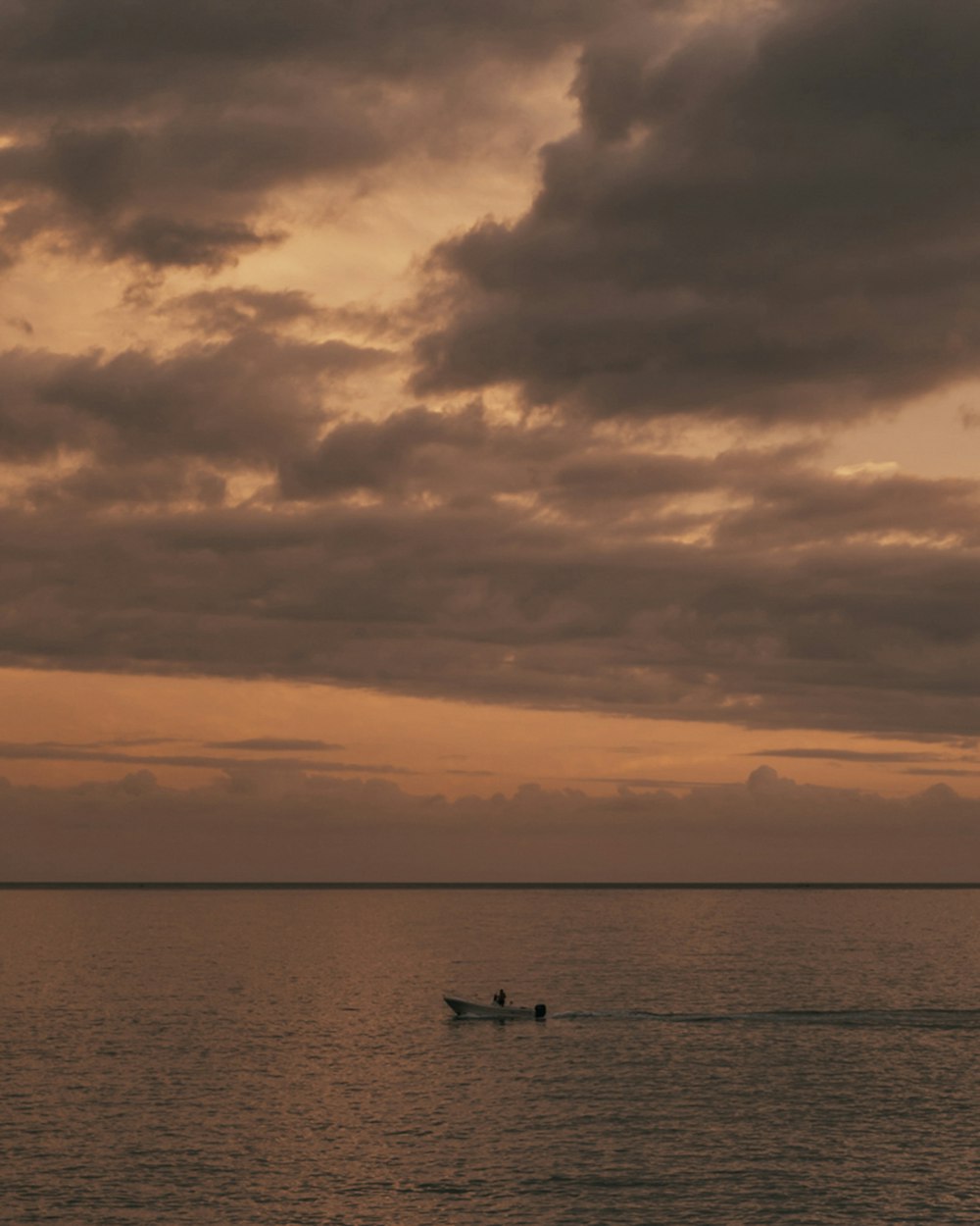 silhueta de 2 pessoas andando de barco no mar sob céu nublado durante o dia