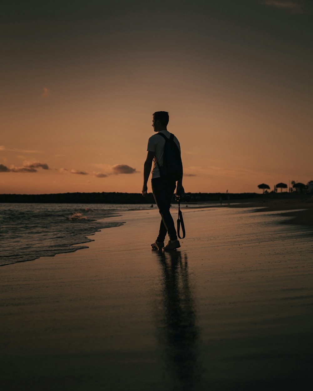 silhouette of man walking on beach during sunset