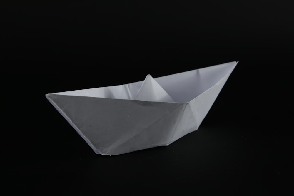 white paper boat on black background