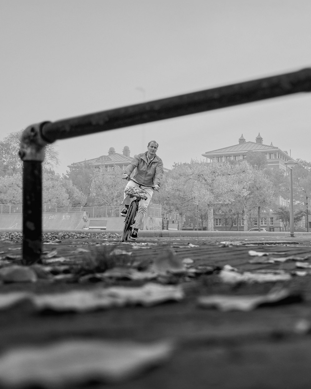 grayscale photo of man in jacket and pants riding skateboard