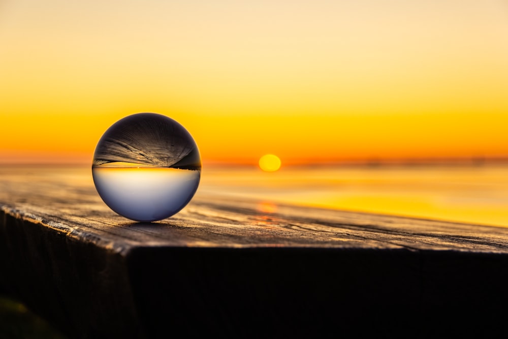 clear ball on brown wooden surface during sunset