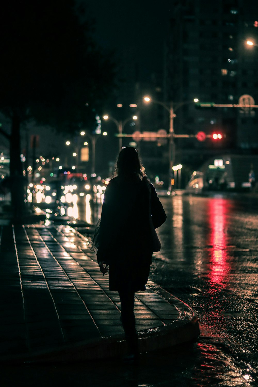 夜間に歩道に立つ黒いコートを着た人