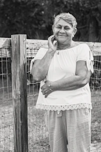 A smiling senior woman wearing a sleek emergency pendant while gardening outdoors.