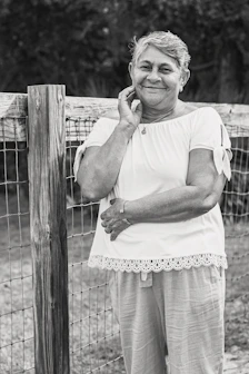 A smiling senior woman wearing a sleek emergency pendant while gardening outdoors.