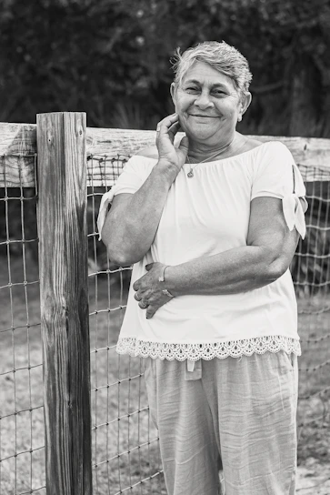 A smiling senior woman wearing a sleek emergency pendant while gardening outdoors.