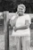 A smiling older woman chatting happily with a neighbor over a garden fence.