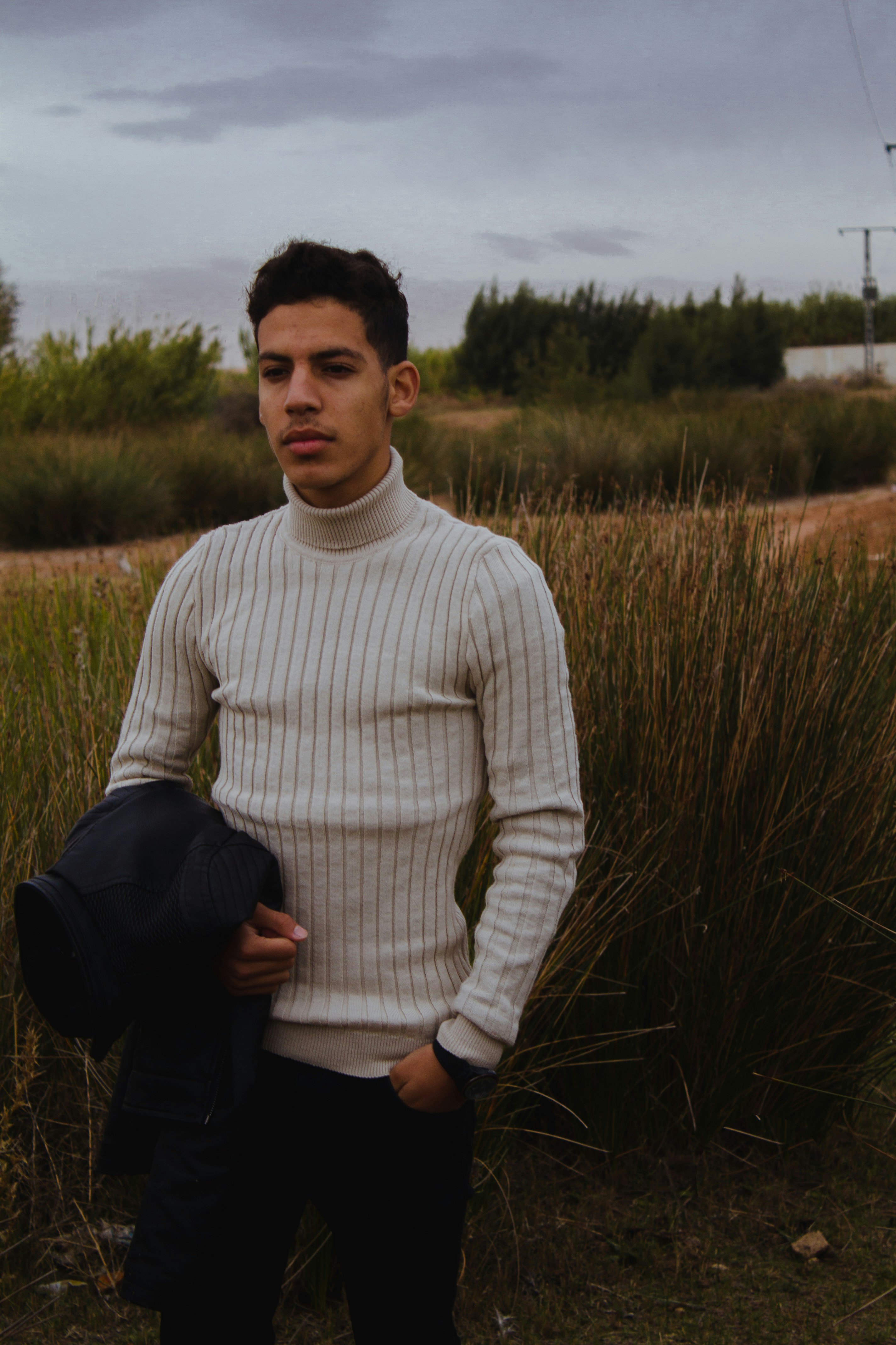 Man wearing a cream merino wool turtleneck sweater, soft neutral studio background