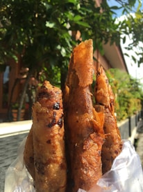 Close-up of crispy spring rolls with dipping sauce on a rustic wooden table.