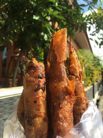 A close-up of golden-brown crispy spring rolls with a side of vibrant dipping sauce.