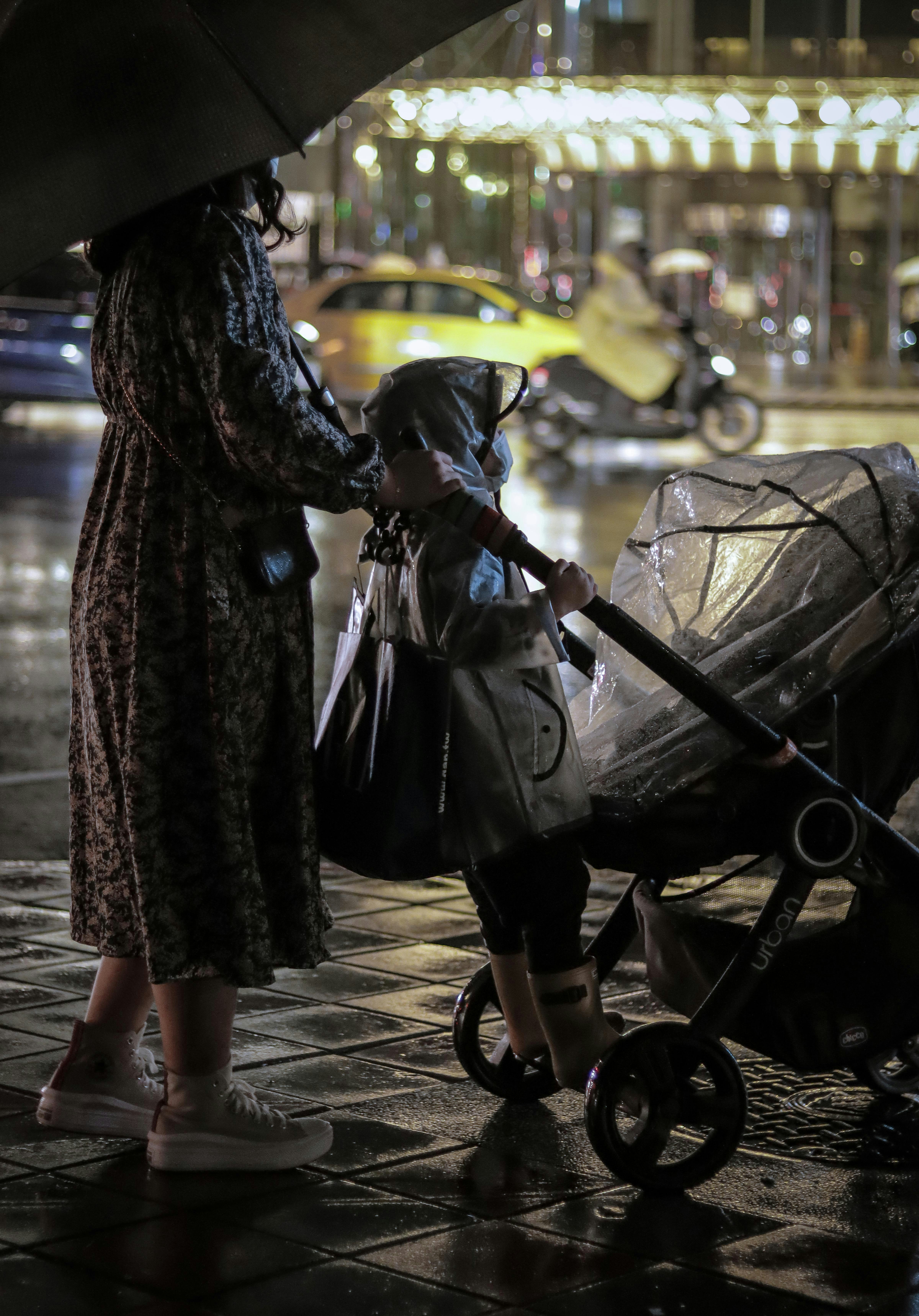 woman in black and white coat standing beside black stroller