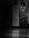 A bottle of Johnnie Walker Black Label blended scotch whisky stands on a polished surface. The image is monochromatic, creating a moody and elegant atmosphere.