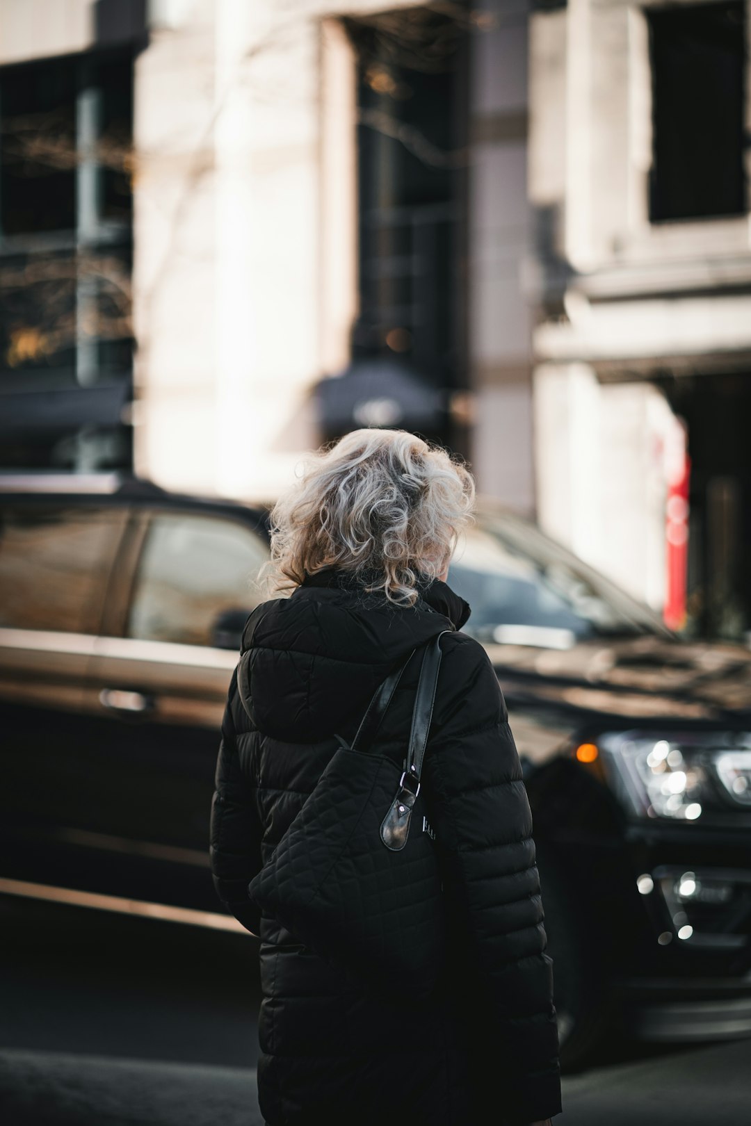 woman in black jacket standing near black car during daytime