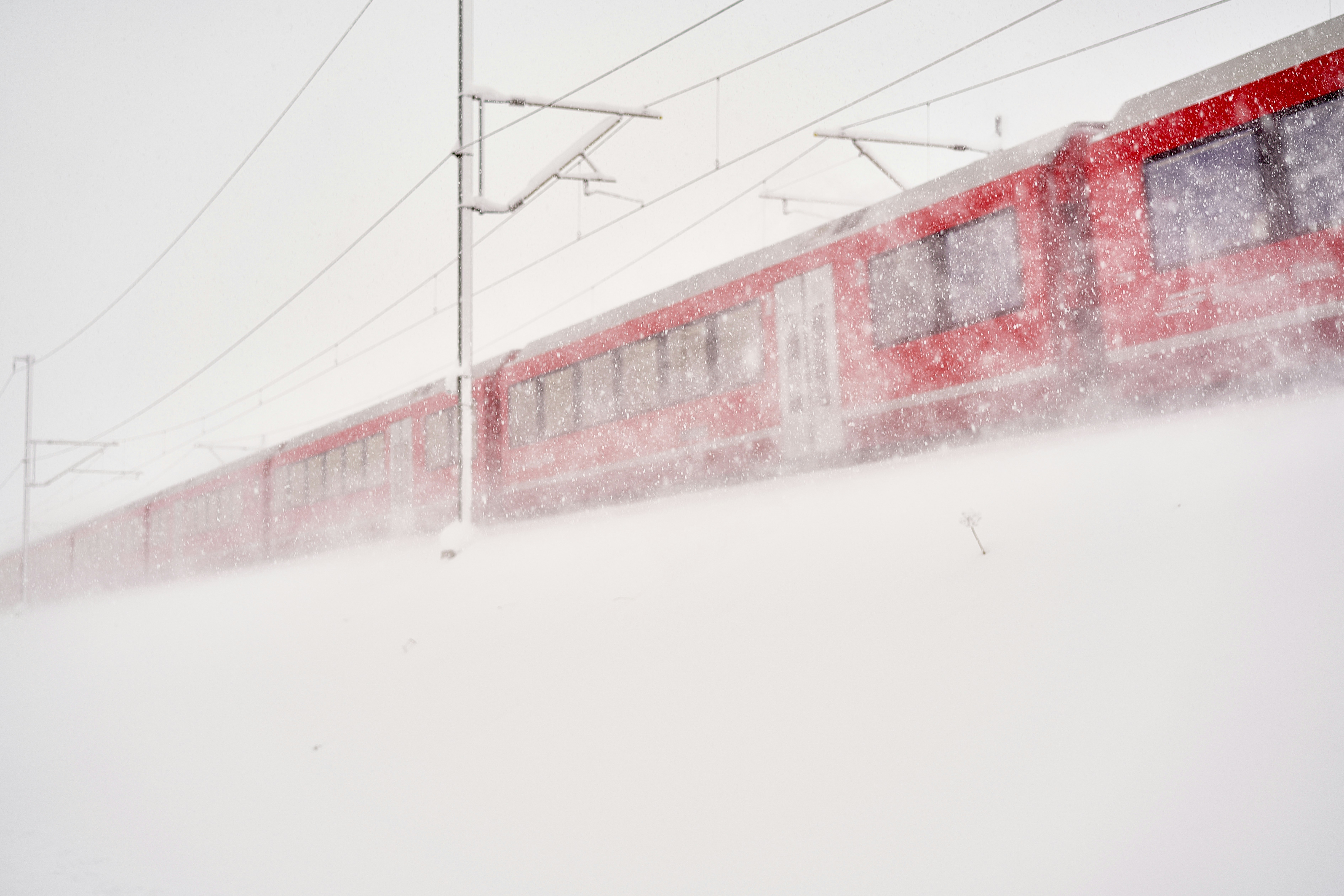 red and white building on snow covered ground, Train passing by in snow storm