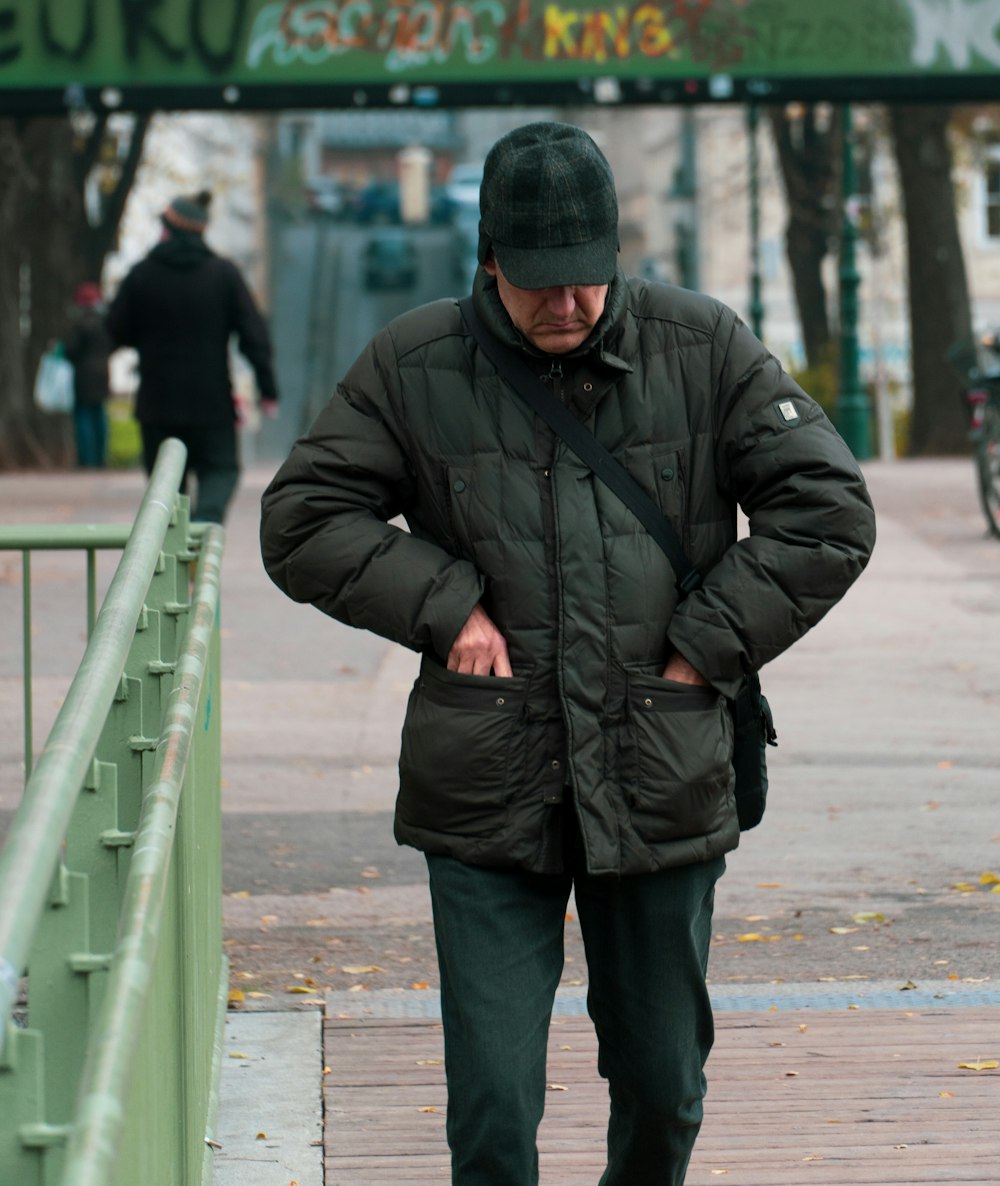 man in black jacket standing on sidewalk during daytime