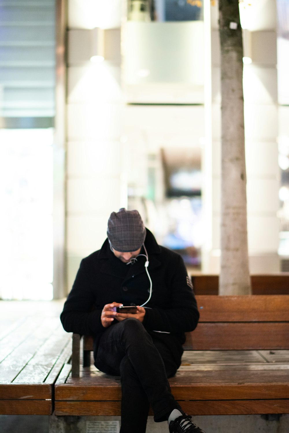 man in black jacket sitting on brown wooden bench