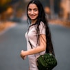 woman in white long sleeve shirt holding green sling bag