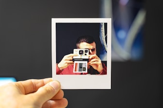 person holding white and red camera