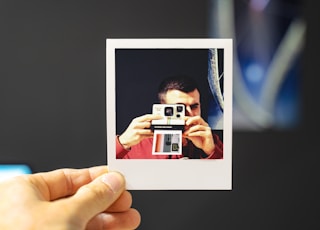 person holding white and red camera