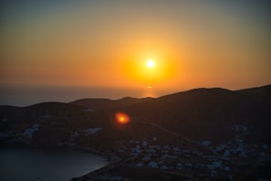 A serene landscape showing a sunset over a peaceful village.