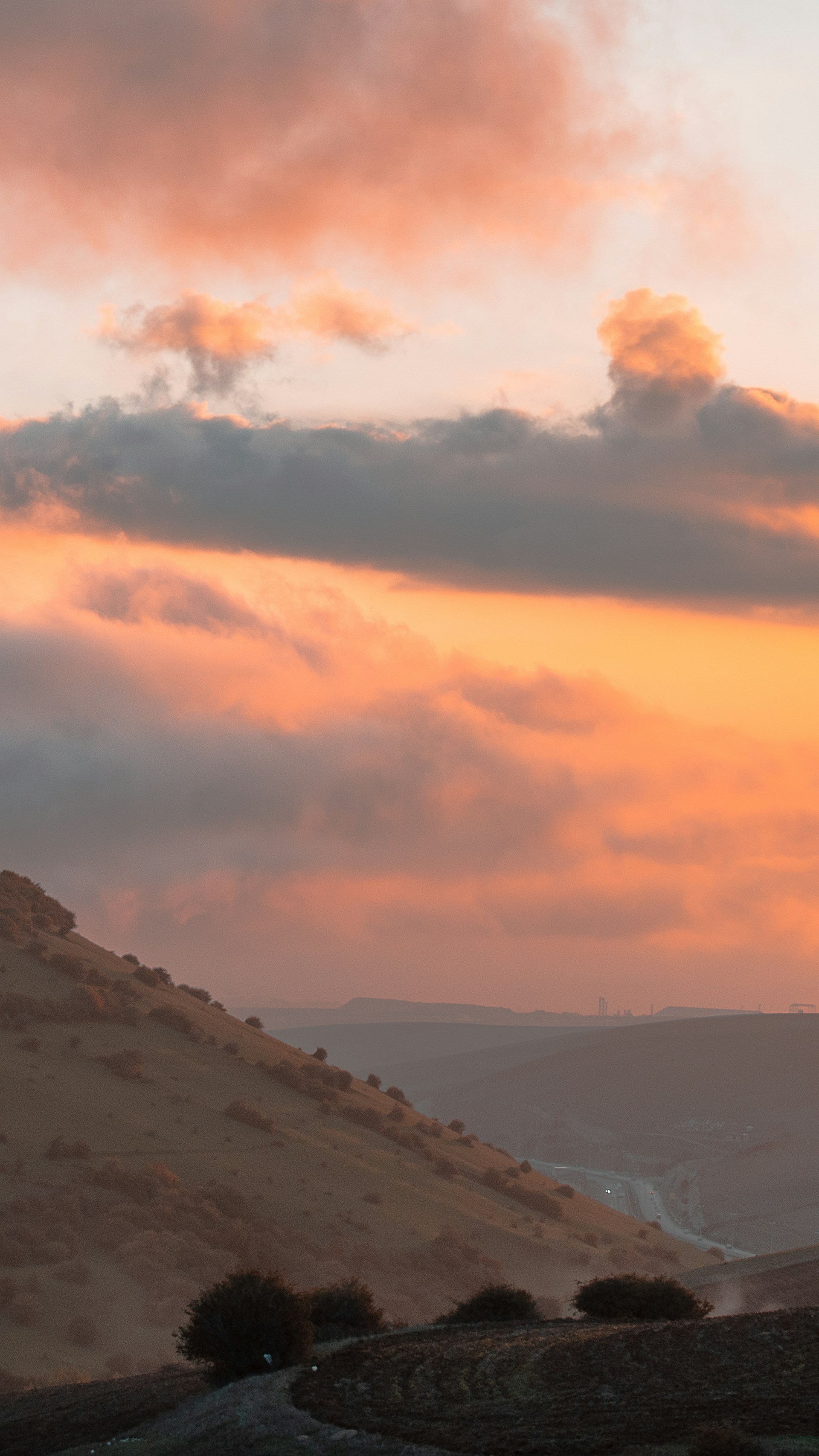 A stunning landscape photograph capturing a serene sunset over rolling hills.
