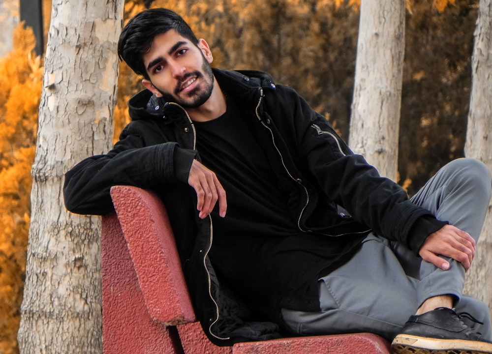 man in black jacket sitting on red chair