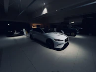 A lineup of exotic cars under soft lighting in a minimalist showroom, emphasizing their sleek silhouettes.