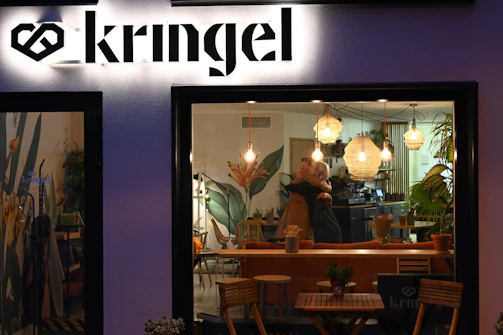 Close-up of a candid embrace between friends in a softly lit terracotta-colored café.