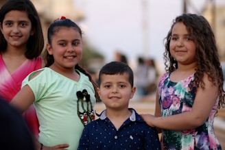 Four kids happily working together in a sunny backyard, pulling weeds and cleaning up leaves.