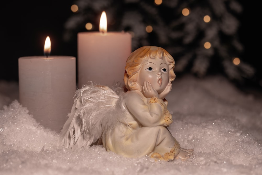 白い柱の蝋燭の横の天使の陶磁器の置物