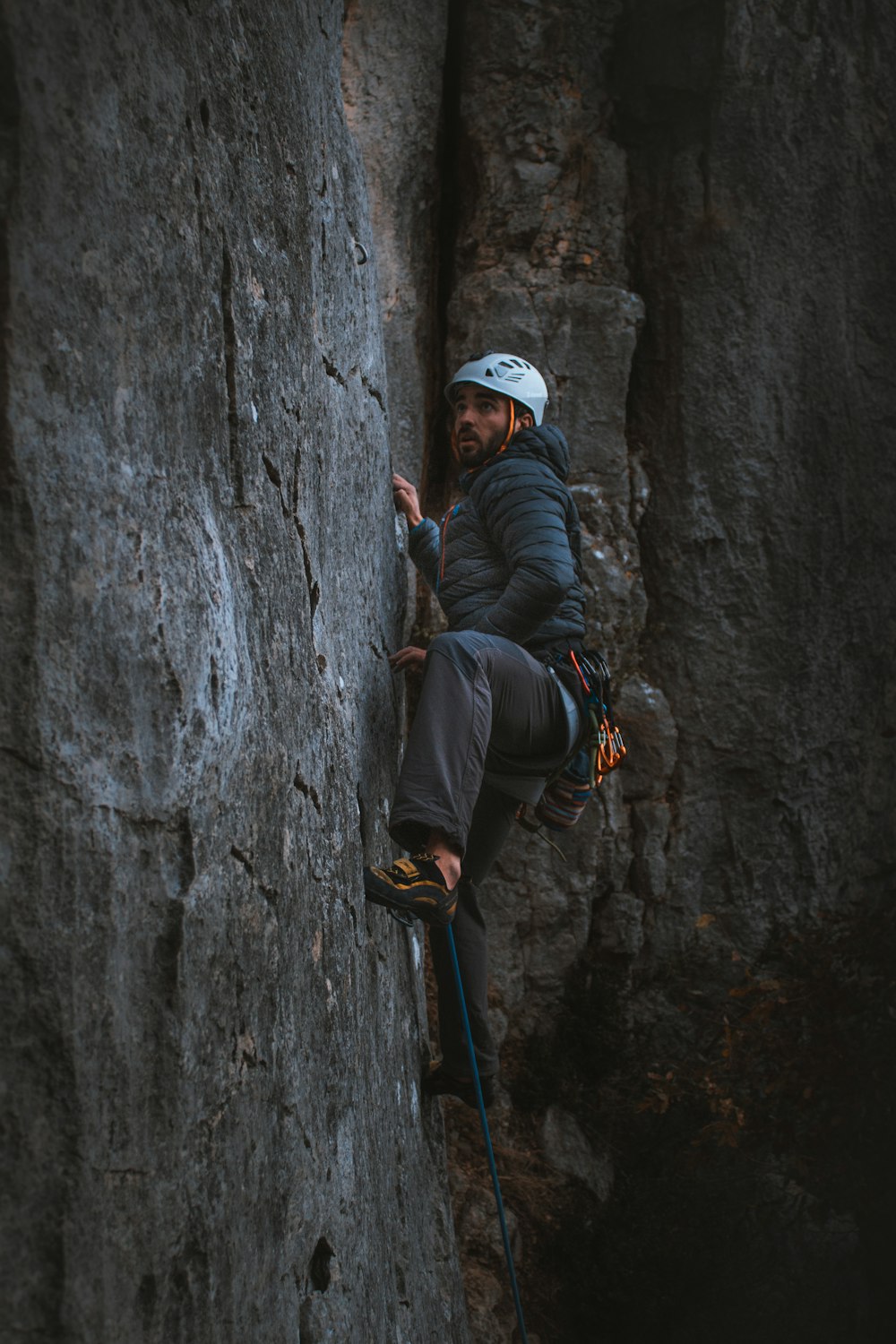 man in black jacket and white cap climbing on gray rock