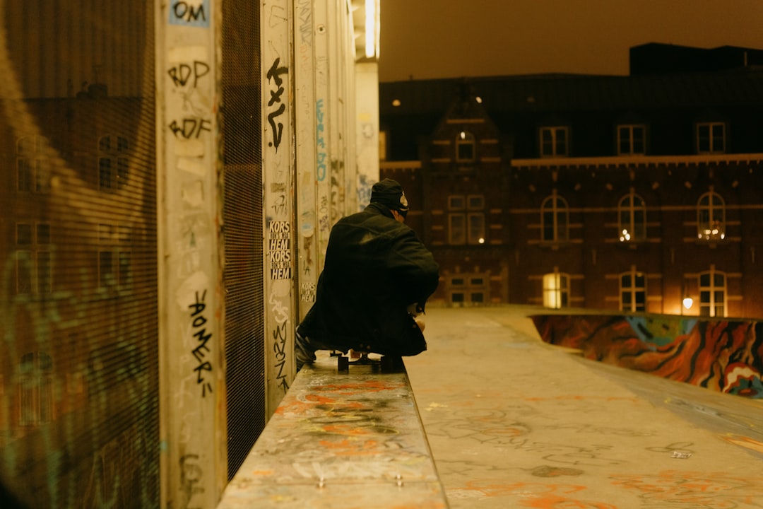 man in black jacket walking on sidewalk during night time