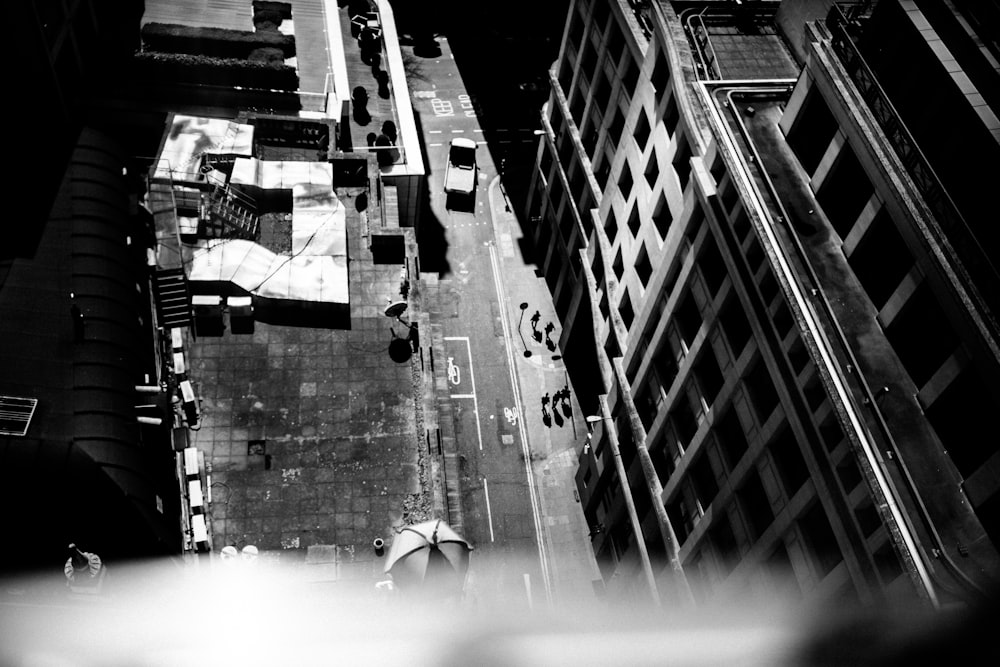 고층 건물 사이의 거리를 걷는 사람들의 그레이스케일 사진
