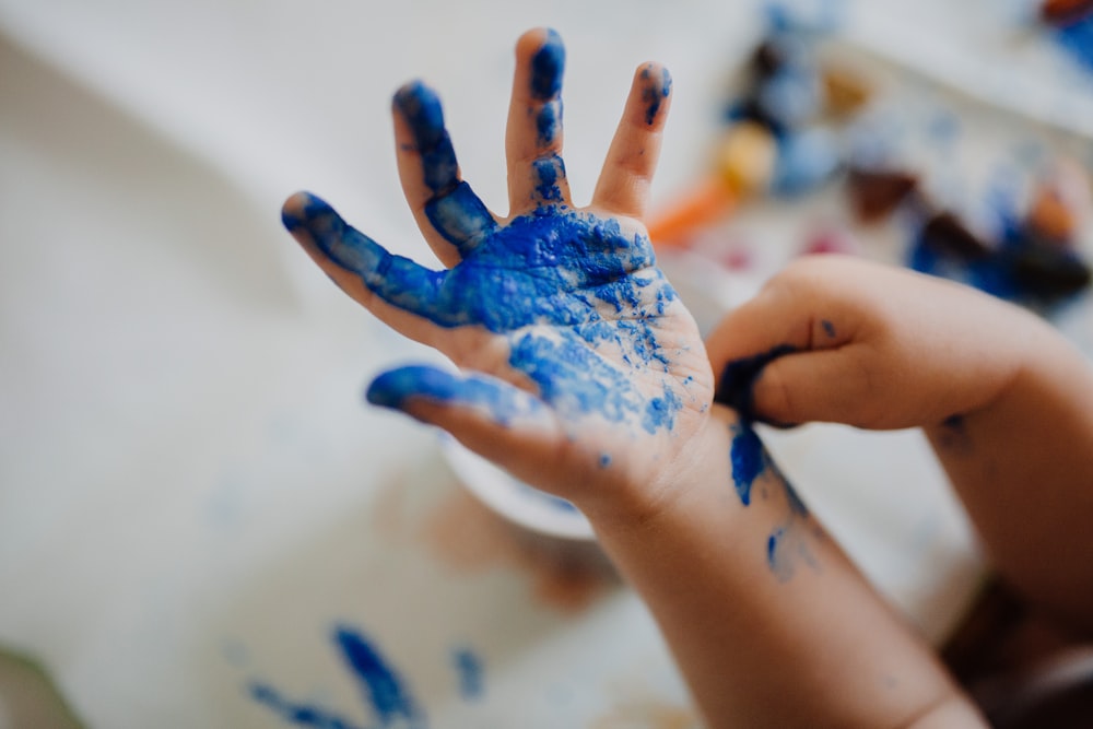 child with blue paint on hand
