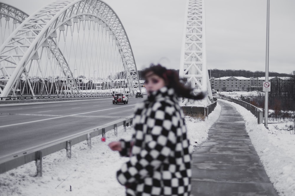 woman in black and white coat standing on gray concrete road near white ferris wheel during