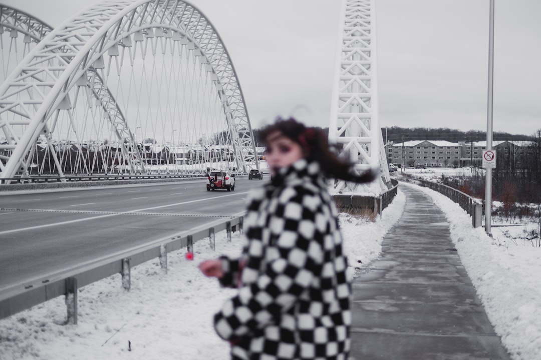 woman in black and white coat standing on gray concrete road near white ferris wheel during