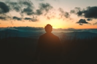 silhouette of man standing on mountain during sunset