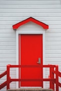 Exterior house painting showing a vibrant red front door and clean white siding.