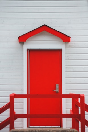 A freshly painted front door with a handyman’s ladder and paint cans beside it.