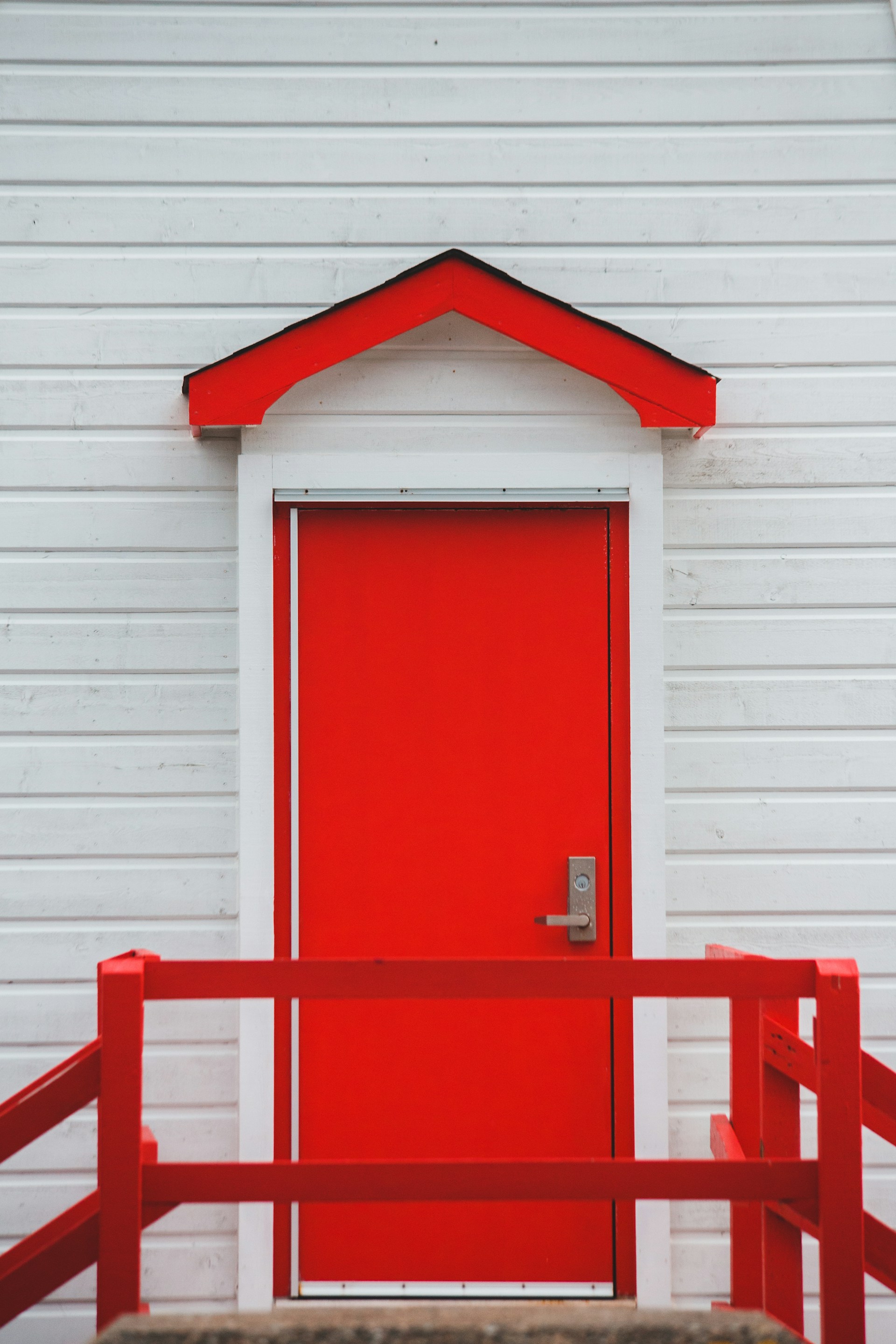 A vibrant front door painted in bold red, contrasting beautifully with the clean modern exterior of a residential home.