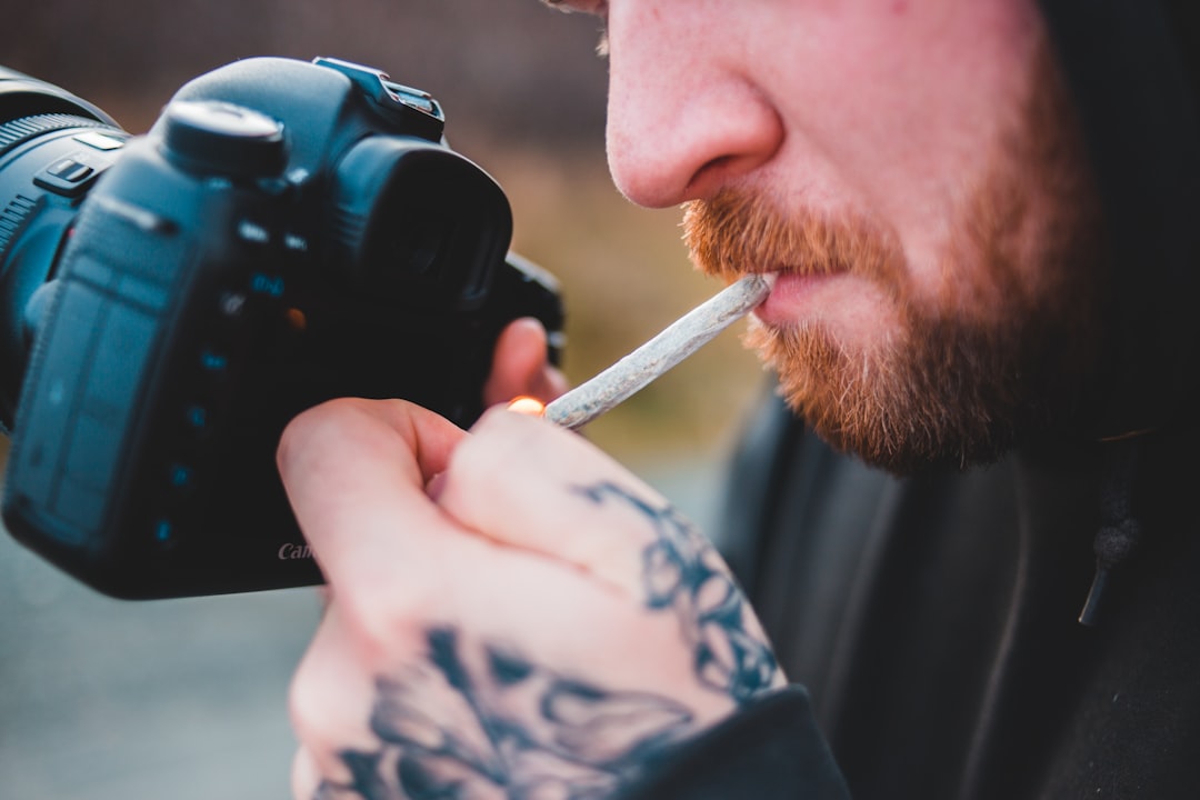 man in blue and white shirt holding black dslr camera