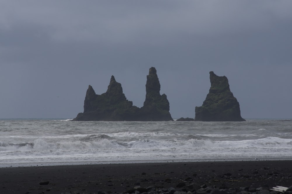 black rock formation on sea during daytime