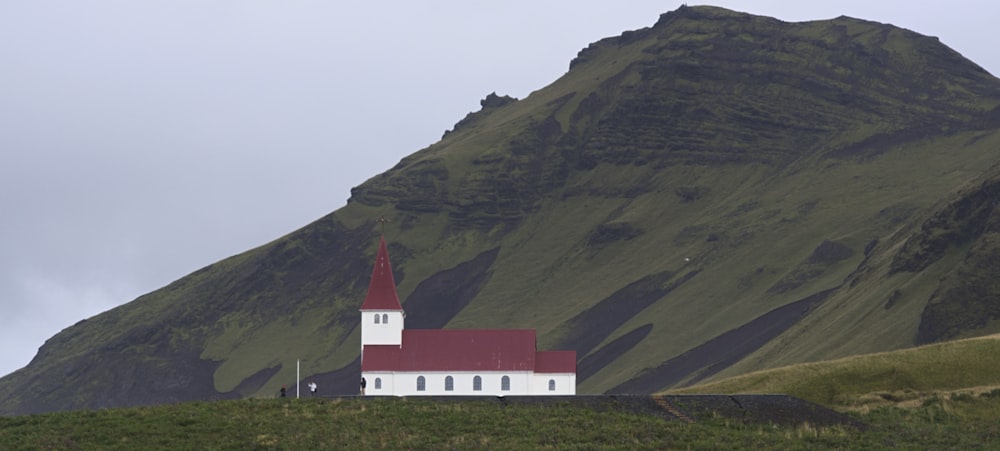 white and red house on green grass field near mountain during daytime