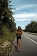 woman in black dress walking on the road during daytime