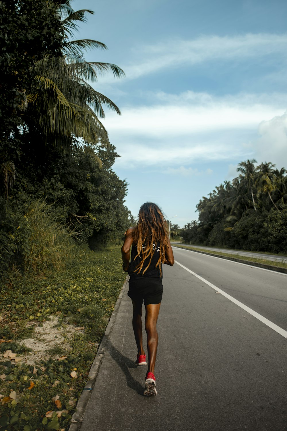 mulher no vestido preto que anda na estrada durante o dia