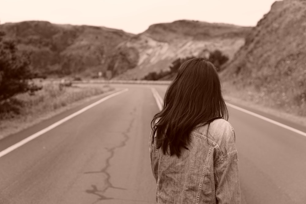 woman in gray denim jacket standing on road during daytime